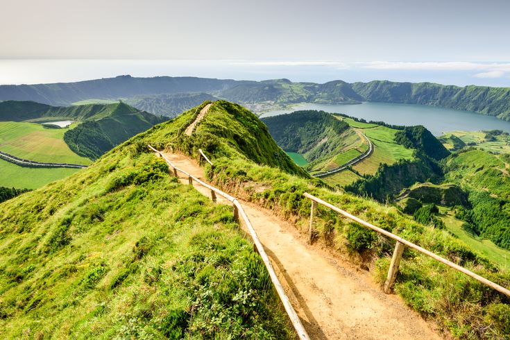 Eine grüne, hügelige Landschaft mit einem Pfad, der sich durch die Hügel schlängelt.