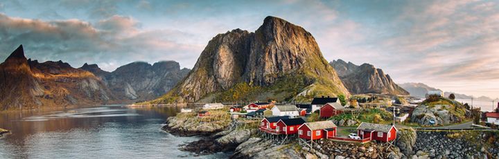 Eine malerische Küstenlandschaft der Lofoten in Norwegen mit einem Dorf und Bergen.
