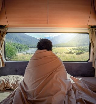 Mann im Wohnmobil unter einer Decke