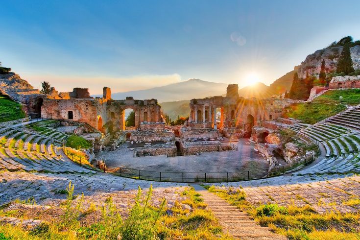Die Ruinen eines antiken Theaters mit Blick auf die Küste und Berge im Hintergrund.