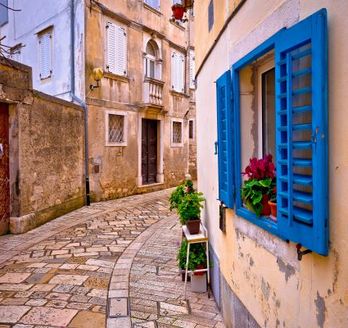 Eine enge Gasse mit Gebäuden und einem blauen Fenster.