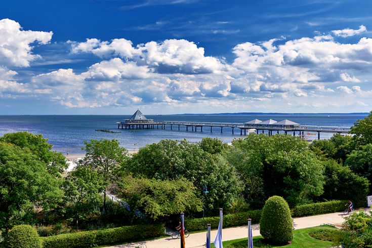 Blick auf Usedom mit seinen Bäumen, einer Promenade und einem Steg welcher ins Wasser reicht.