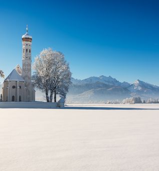 Die Kirche St. Coloman im Schnee an einem sonnigen Wintertag, Allgäu