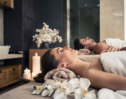 Eine entspannende Spa-Umgebung mit einer Badewanne, die mit Blütenblättern gefüllt ist, und Kerzen, die eine ruhige Atmosphäre schaffen.