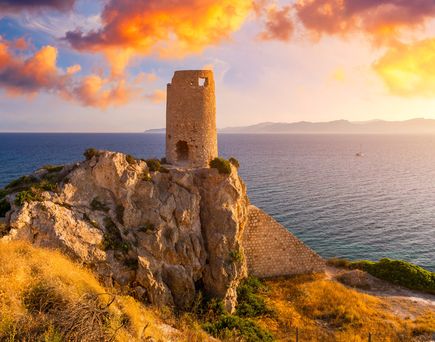 Ein Turm auf einer Klippe bei Sonnenuntergang.