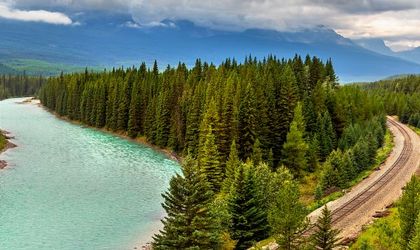 Eine Landschaft mit einem Fluss, der sich durch einen Wald schlängelt.