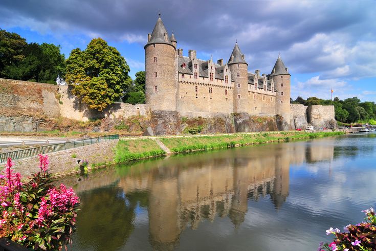 Schloss Josselin, umgeben von Wasser und blauem Himmel.