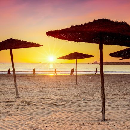Strand von Agadir im Sonnenuntergang und Sonnenschirme