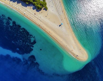Eine Luftaufnahme einer Sandbank, die ins türkisfarbene Meer ragt.