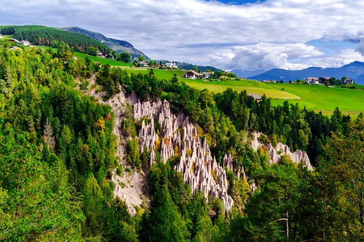 Eine Luftaufnahme von Erdpyramiden in Südtirol, umgeben von grüner Landschaft.