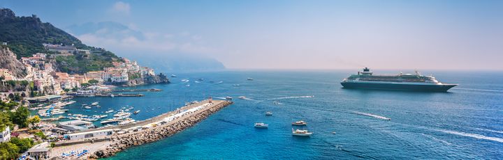 Kreuzfahrtschiff fährt durch das Meer mit Strand im Vordergrund
