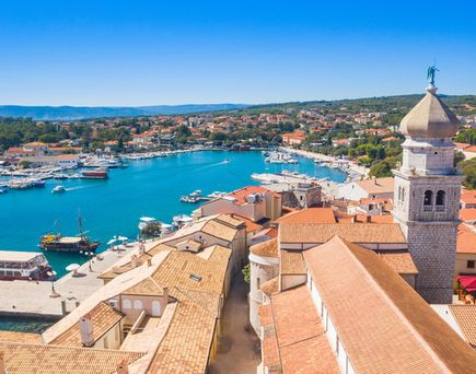 Eine Luftaufnahme der Stadt Krk, Kroatien, mit roten Dächern und Blick auf das Meer.