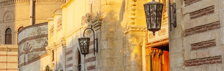 Die historische Hängende Kirche (Church of St. George) in Kairo, mit ihrer markanten Architektur und einem runden Kuppelbau im Hintergrund, bei hellem Tageslicht.