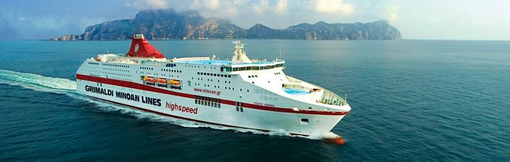 Ein großes, weißes Fährschiff mit roten Streifen und dem Logo "Minoan Lines" auf dem Schornstein fährt auf einem ruhigen blauen Meer.