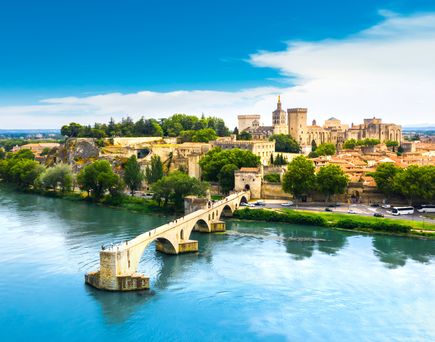 Blick aus der Vogelperspektive auf Avignon mit seinen alten Gemäuern und einem Steg.