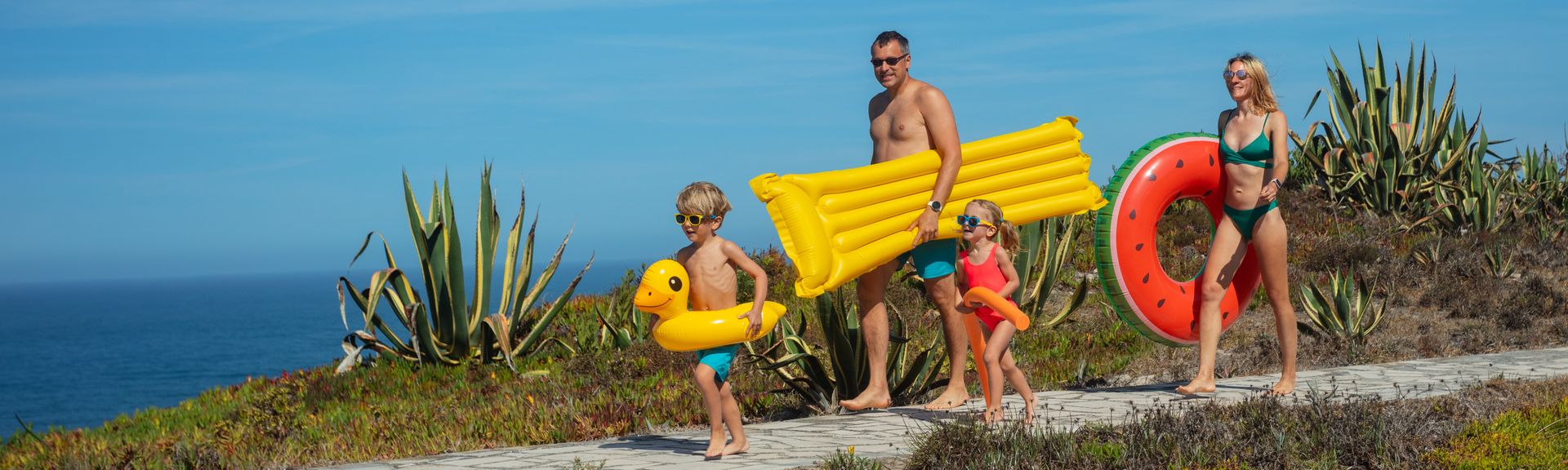 Familie geht mit Strandspielzeug an den Strand
