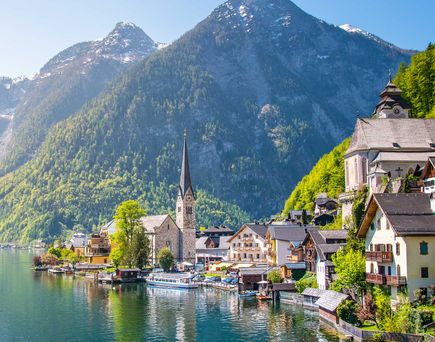 Dorf mit Kirche am Seeufer im Sonnenlicht