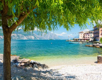 Strand am Gardasee mit Stadtz und Bergen im Hintergrund