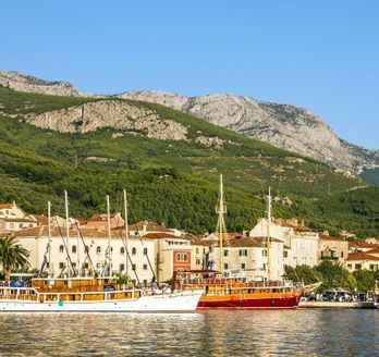 Eine Hafenstadt mit Booten und Gebäuden am Wasser, umgeben von Bergen.