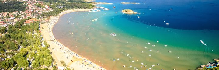 Eine Luftaufnahme einer Insel mit einem Strand und türkisfarbenem Wasser.