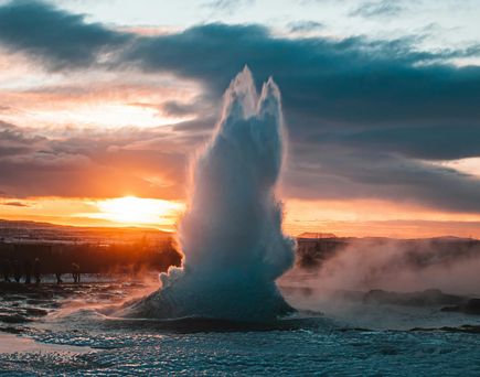 Geysir spritzt in die Höhe im Hintergrund ein Sonnenuntergang