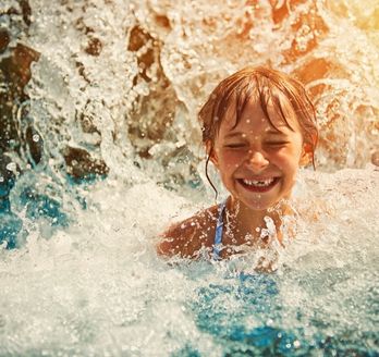Lachendes Kind im Schwimmbad eines Wasserparks.