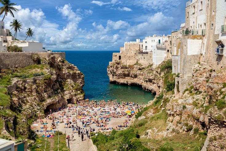 Blick auf Polignano a Mare mit seinen antiken Häusern und einem Strandabschnitt.