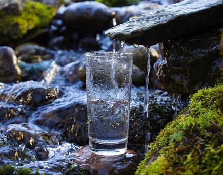 Gläser mit Wasser werden von einem Wasserfall gefüllt.