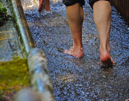 Füße gehen auf einem Kiesweg mit Wasser.