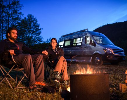 Ein Campingplatz mit einem Lagerfeuer und einem Wohnmobil.