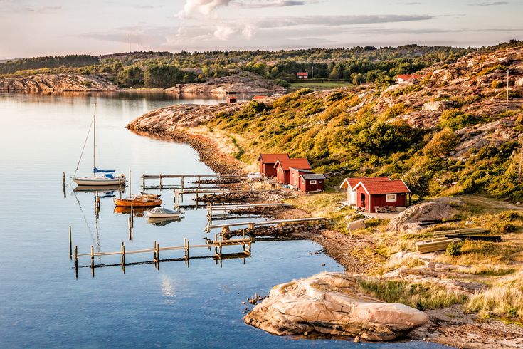 Eine malerische Küstenlandschaft mit bunten Häusern, die sich an einen Hang schmiegen, und Booten im ruhigen Wasser. Die Szene ist lebhaft und einladend.
