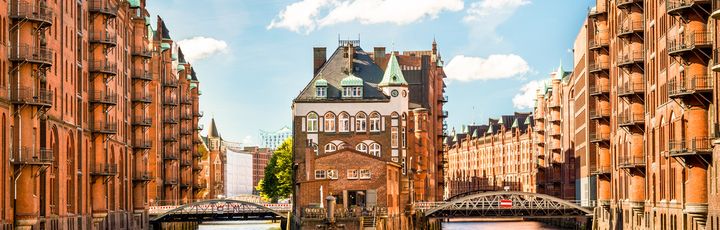 Historische Gebäude am Hafen von Hamburg mit einem Schiff und dem Wasser im Vordergrund.