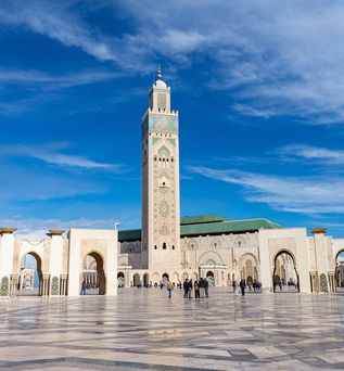 Blick über einen weiten Platz auf einen weißen Turm in Casablanca