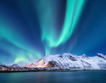 Polarlichter über schneebedeckten Bergen in Tromso