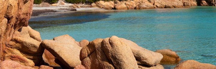 Ein Strand mit türkisfarbenem Wasser und Felsen.