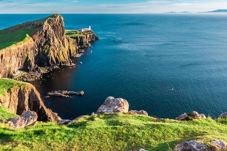 Eine felsige Insel mit einem Berg und einem alten Gebäude. Die Insel ist von blauem Wasser umgeben.
