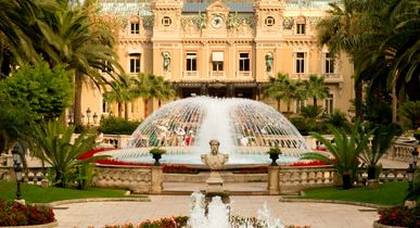 Ein prunkvolles historisches Gebäude mit einem Brunnen und einem gepflegten Garten. Die Architektur ist symmetrisch und beeindruckend.