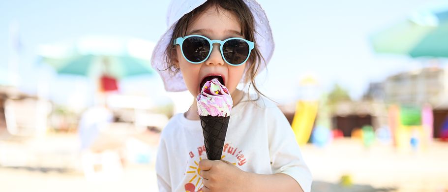 KLeinkind sitzt am strand und isst ein eis