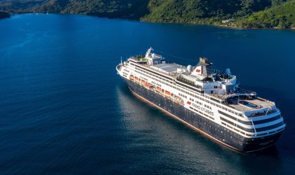 Ein Kreuzfahrtschiff fährt durch einen Fjord, umgeben von steilen Bergen.