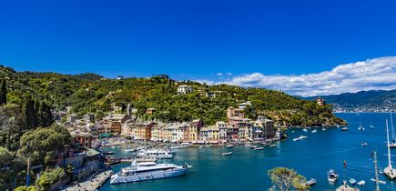 Luftaufnahme der malerischen Hafenstadt Portofino in Ligurien, Italien, mit bunten Häusern und Yachten im klaren Wasser.