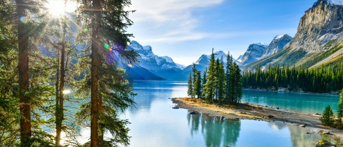 Bild vom glaklaren See mit Bäumen und umgeben von Bergen in Kanada