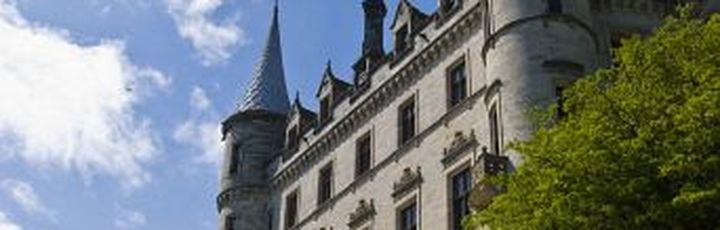 Eine historische Architektur mit einem Schloss und einem Turm. Die Gebäude sind aus Stein und wirken alt.