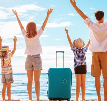 Familie am Strand mit Koffern 