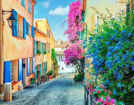 Schmale Gasse mit bunten Häusern und bunten Blumen, blaue Fensterläden