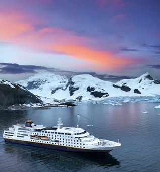 Kreuzfahrtschiff fährt durch das Meer mit Bergen im Hintergrund