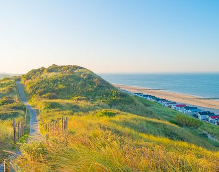 Eine hügelige Landschaft mit Gras und einem Fluss oder Meer.