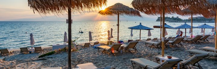 Sonnenuntergang am Siviri Strand. Liegen, Sonnenschirme und Schwimmer.