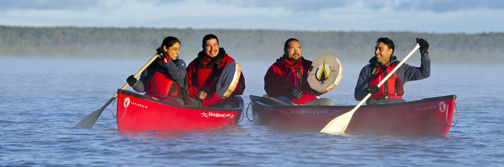 Vier Personen sitzen in roten Kanus und machen eine Fahrt vor Manitoulin Island