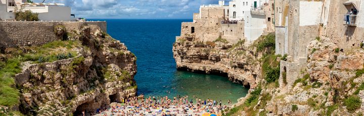 Blick auf Polignano a Mare mit seinen antiken Häusern und einem Strandabschnitt.