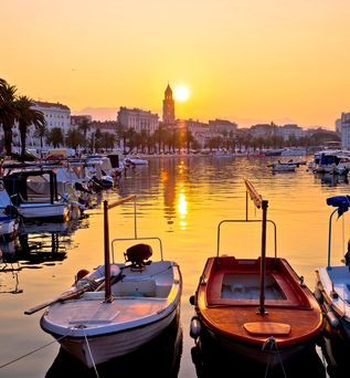 Eine malerische Küstenansicht von Split, Kroatien, bei Sonnenaufgang, mit der Stadt, die sich am Ufer des Adriatischen Meeres ausbreitet, und Bergen im Hintergrund.